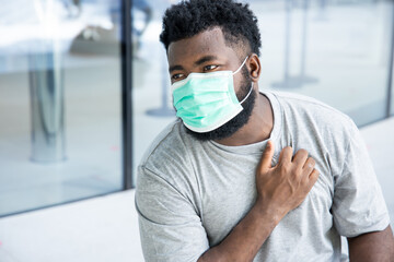 Symptometic black african man wearing hygienic face mask and having breathing difficulties
