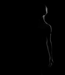 Black and white silhouette of a beautiful woman seen one half of the body on a dark background.
