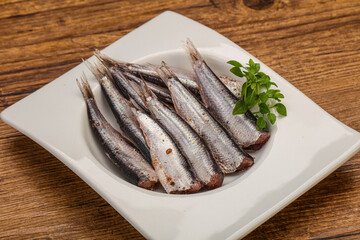 Anchovies in the bowl served basil leaves