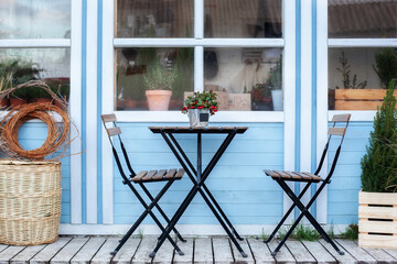 Wooden table and chairs on veranda of house. there is potted Christmas mistletoe on table in street...