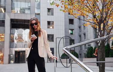 Town style clothes. Beautiful young european woman is outdoors in the city at daytime