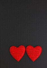 Two red hearts on a black background. Festive background. Minimalism. Copy space. St. Valentine's Day background