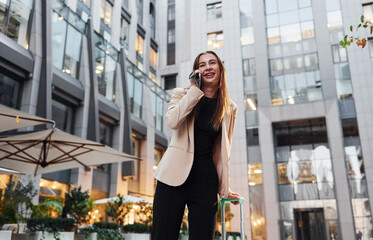 Town style clothes. Beautiful young european woman is outdoors in the city at daytime