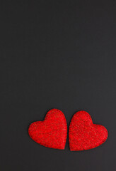 Two red hearts on a black background. Festive background. Minimalism. Copy space. St. Valentine's Day background