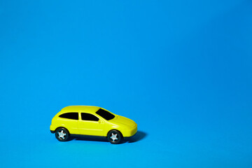 yellow toy car on blue background, concept idea of taxi and cargo delivery during quarantine
