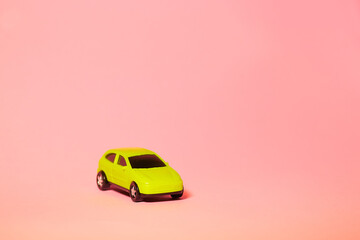 yellow toy car on pink background, concept idea of taxi and cargo delivery during quarantine