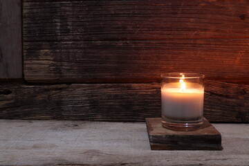 the burning luxury aromatic scented candle glass on the wooden table with background of vintage...