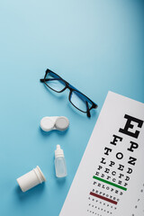 Ophthalmic Accessories Glasses and lenses with an Eye Test Chart for vision correction on a blue...