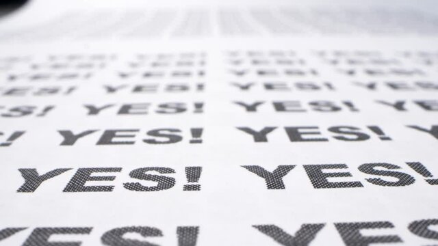 text background. extremely close-up, detailed. typing the word yes with an exclamation mark printed on white paper in black