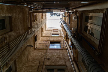 Fototapeta premium Well in courtyard of old buildings with windows, pipes and daylight