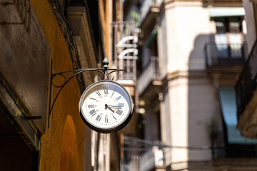 Fototapeta na wymiar Street clock with arrows on wall with background of buildings in Barcelona