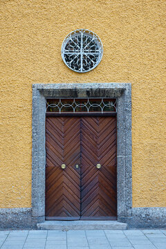 wooden front door and yellow rough house facade