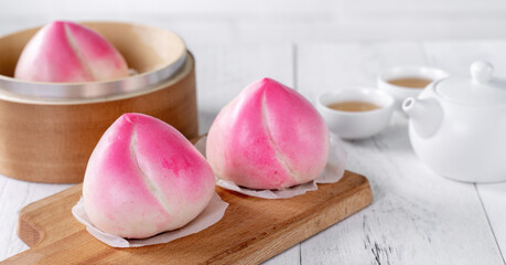 Pink Chinese peach birthday bun food on white table background.