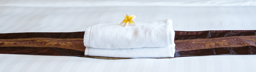 A hotel maid stacked towels on the bed and placed flowers on the towels in a hotel room