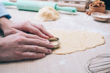 Girl making cookies in the shape of a heart in the kitchen, close-up. Surprise for your loved ones on Valentine's day, mother's Day or father's Day. Festive culinary background, with love