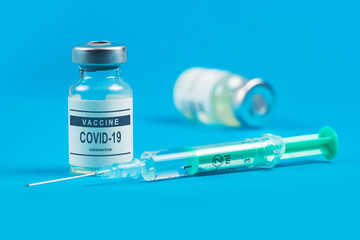 Vaccination. Syringe and vaccine COVID-19. Coronavirus on blue background