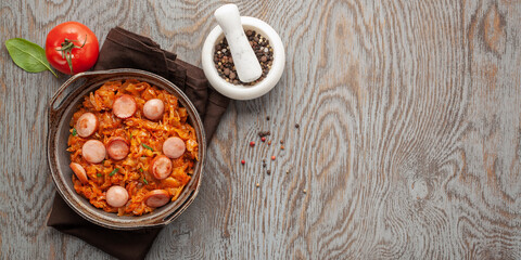 Cabbage stew with grilled sausage in tomato sauce - traditional dish of German, Polish or Russian cuisine Bigos. Top view