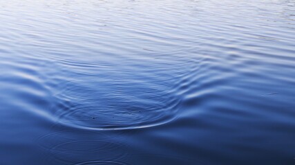 Tranquil lake water with smooth ripple surface and blurry reflection. Defocused blue wavy water background with copy space