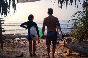 surfing couple checking waves on a warm tropical beach