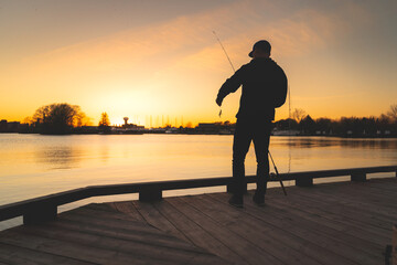 Silhouette of a fisherman resetting his lure