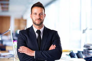 Portrait shot of executive businessman wearing suit and tie while standing with arms crossed in the...