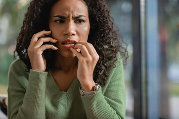 Fototapeta na wymiar worried african american woman talking on smartphone in cafe