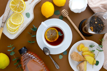 Tea with lemon, honey and ginger on a brown table, flat lay