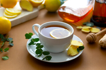 Tea cup with lemon, honey and ginger on a brown table, copy space.
