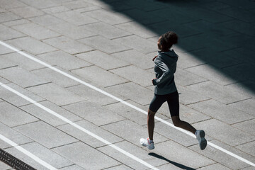 Fast runner. Young african american woman in sportive clothes have workout outdoors at daytime