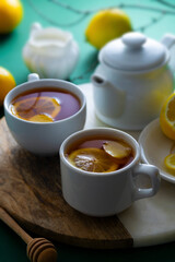 Tea cups with lemon, honey and ginger on green table, copy space.
