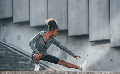 Fototapeta premium Conception of sport. Young african american woman in sportive clothes have workout outdoors at daytime