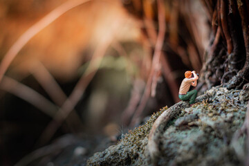 Miniature photographer taking photo of beautiful landscape