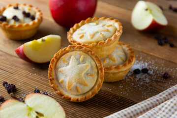 Mince pies with raisins and cinnamon on wooden background