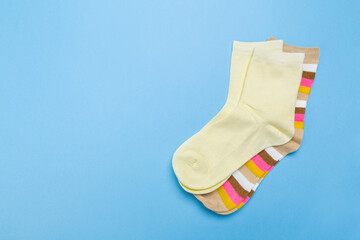two pairs of multicolored new socks stacked on a blue background. top view.
