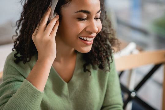 Happy African American Woman Listening Podcast In Cafe