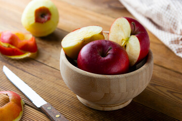 Red apples slices in a bowl on wooden rustic table.
