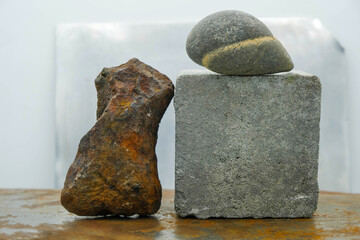Gray cement paving brick, ocher stone, and natural grey stone boulder on a rusty metal surface....