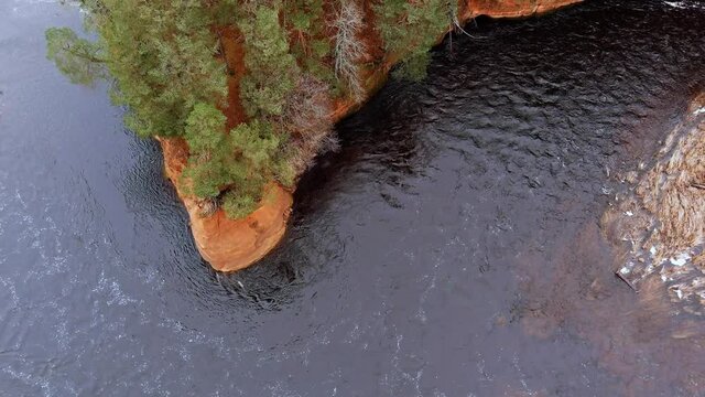 Red sandstone cliffs in the banks of river Salaca during late autumn time, Latvia. Real time drone footage