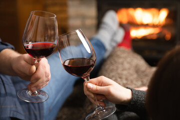 Couple in love sitting in a cozy room with fire place on a sofa with glass of wine. Family and love...