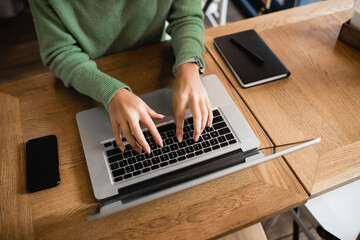 cropped view of african american woman typing on laptop keyboard in cafe