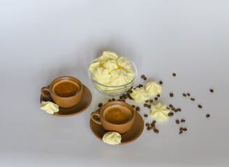 A cup of coffee, a delicate meringue dessert and coffee beans on a light background