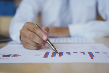 Asian male finance staff Is explaining the performance from the company's rapidly growing bar graph this year. To his boss On the desk at the office, Finance concept