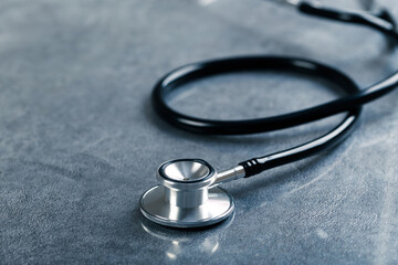 Black stethoscope for doctor diagnostic coronavirus disease, medical tool for health on blue background with copy space