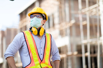 Asian construction worker on building site. wearing surgical face mask during coronavirus and flu outbreak