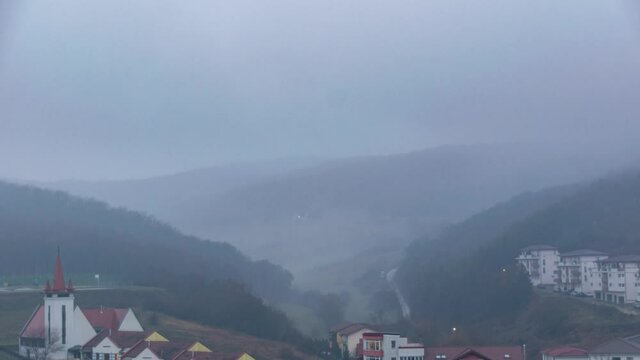 Small town against misty montain at sunset. Timelapse
