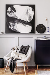 Interior design of living room with stylish armchair, plaid, black clock, cacti, marble stool, modern paintings, decoration and beautiful dog lying on the armchair.