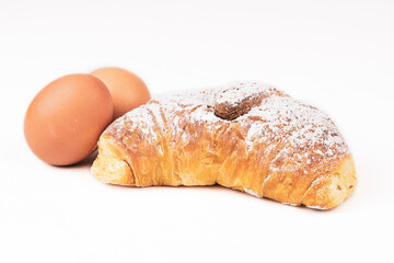 freshly baked croissant with powdered sugar isolated on white background ready for breakfast