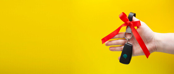 Woman's hand holds car keys. Car keys as a gift on a yellow background