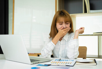 Asian female finance workers are yawned because they are sleepy from overtime. While checking income accounts Loss expenditures for finance companies In her office, the financial concept had a problem