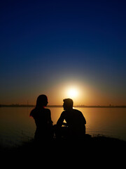 Fototapeta na wymiar silhouette of a romantic loving couple at sunset. lake in the background